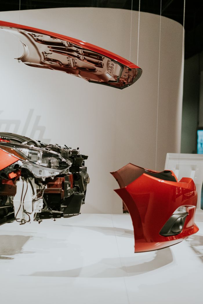 A detailed view of disassembled car parts hanging in a modern exhibit setup.