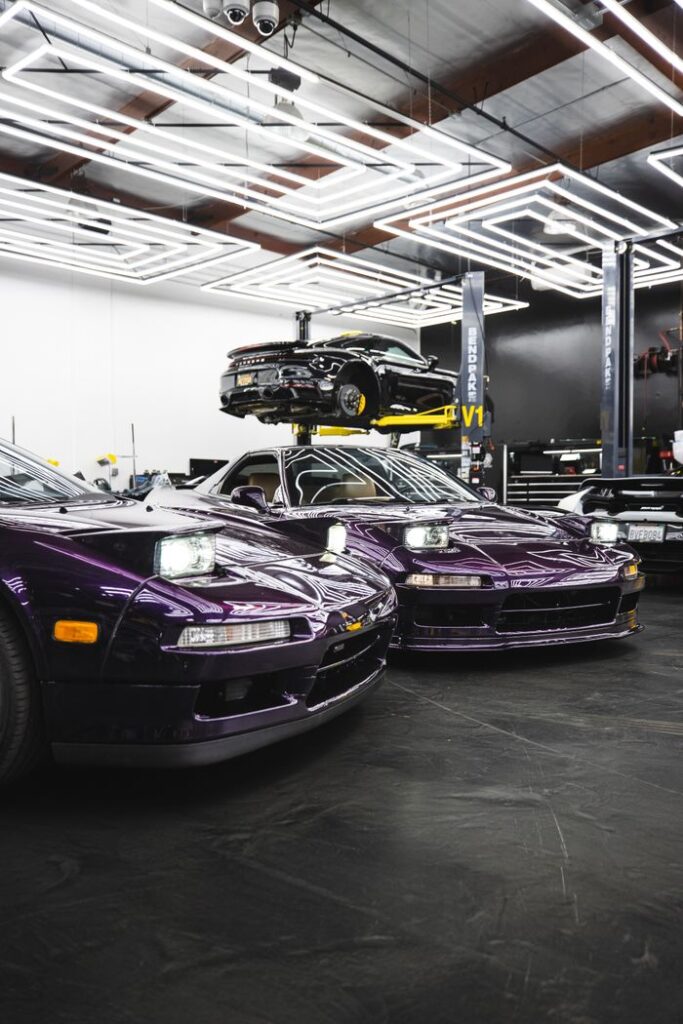 Purple sports cars showcased in a sleek, modern garage with vibrant lighting.
