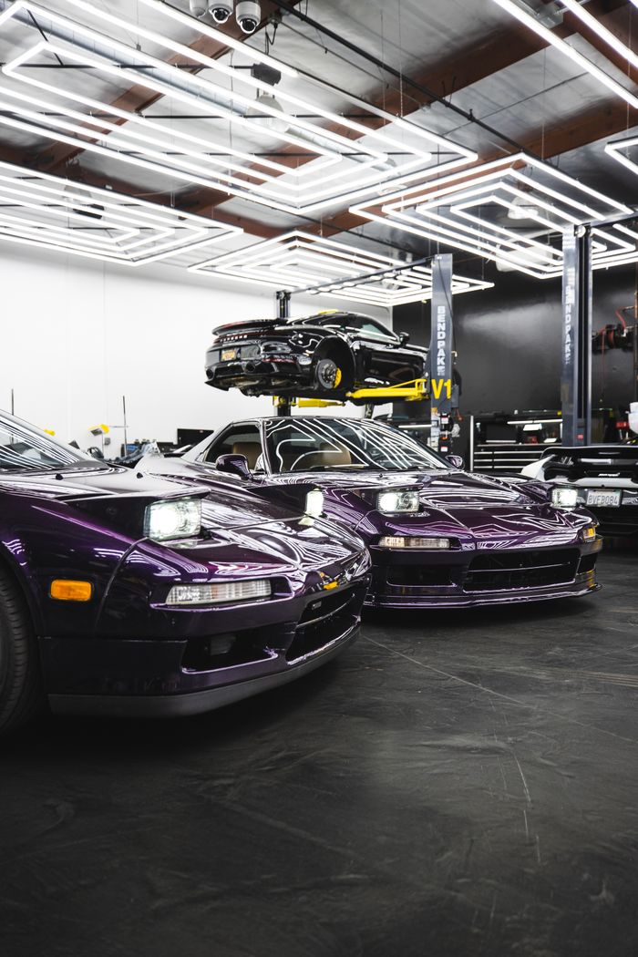 Purple sports cars showcased in a sleek, modern garage with vibrant lighting.